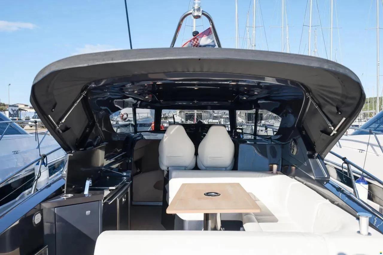 Luxury 2023 Focus Power 36 yacht interior with seating and table, docked at marina.