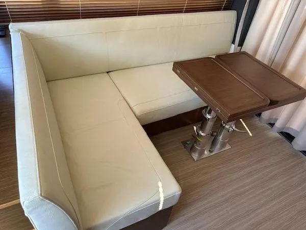 This Could Be Yours Yacht Photos Pics 2023 Bavaria R40 Coupe interior with beige seating and wooden table.