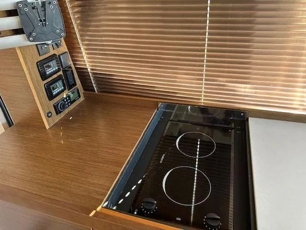 This Could Be Yours Yacht Photos Pics 2023 Bavaria R40 Coupe interior with modern stove and control panel, featuring wooden finishes.