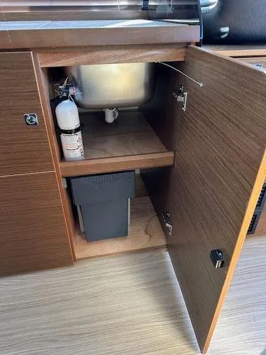 This Could Be Yours Yacht Photos Pics 2023 Bavaria R40 Coupe interior cabinet with fire extinguisher and waste bin.