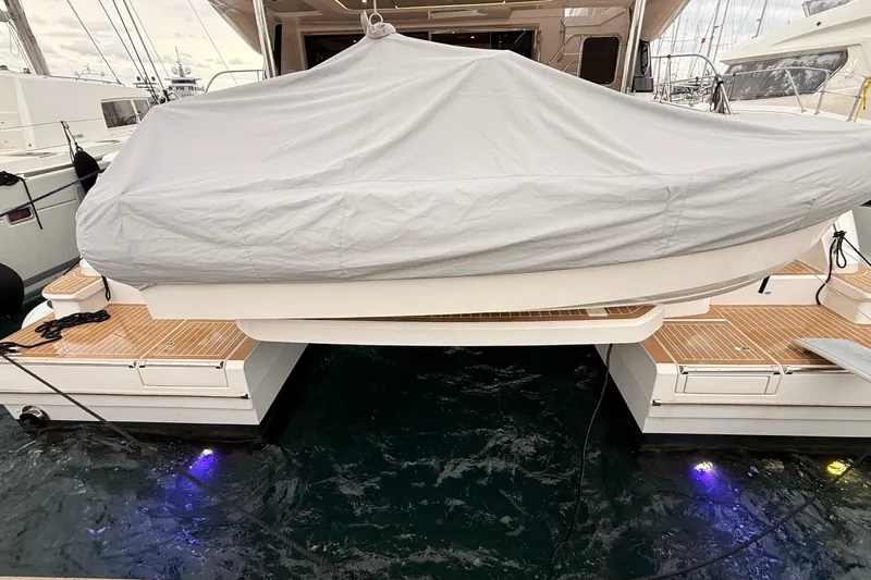  Yacht Photos Pics 2025 Aquila 50 Yacht with covered tender on teak deck, docked at marina.