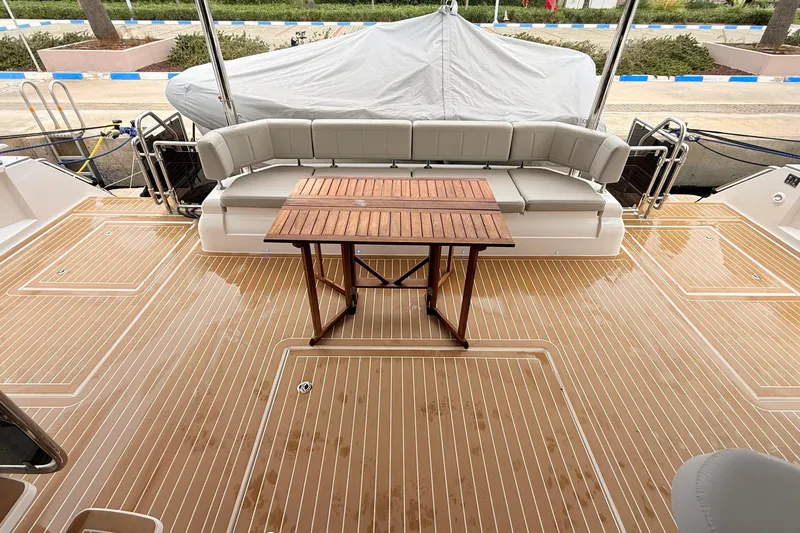  Yacht Photos Pics 2025 Aquila 50 Yacht deck with wooden table and cushioned seating.