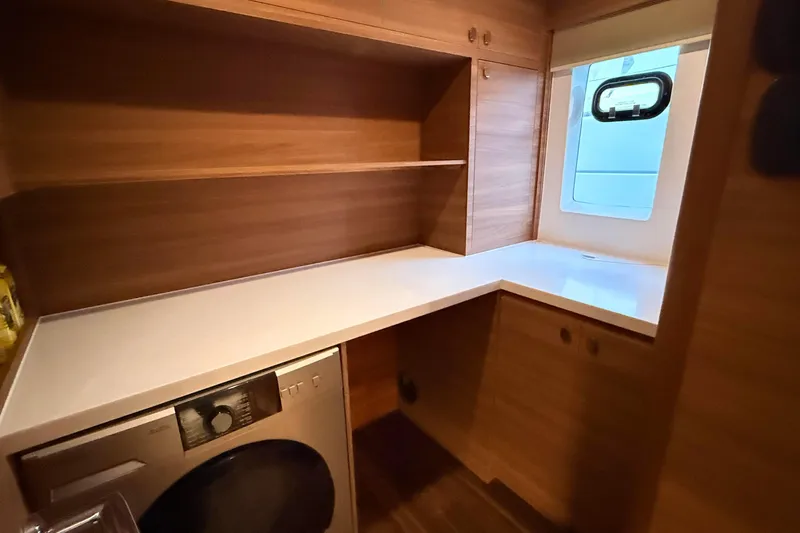  Yacht Photos Pics Laundry area in 2025 Aquila 50 Yacht with washer, wooden shelves, and window.