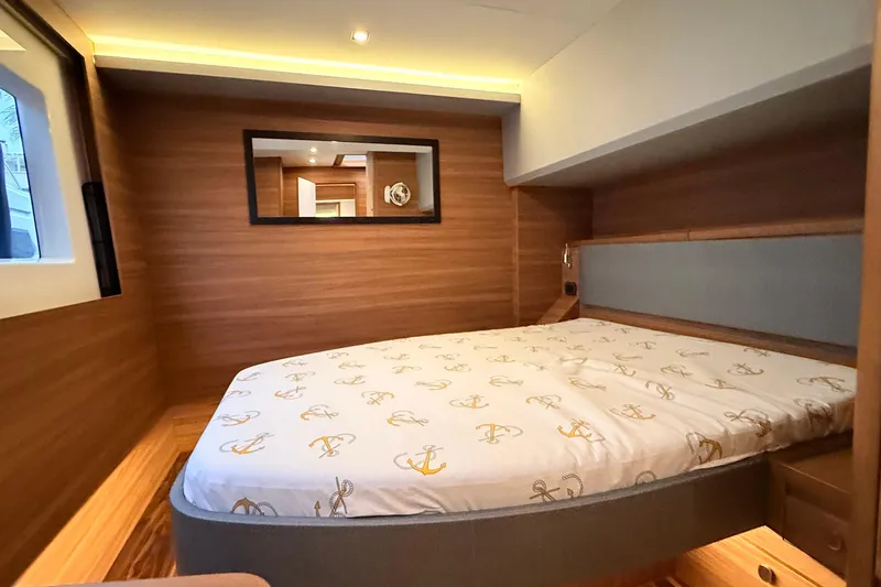 Yacht Photos Pics Luxurious cabin interior of 2025 Aquila 50 Yacht with wood paneling and cozy bedding.