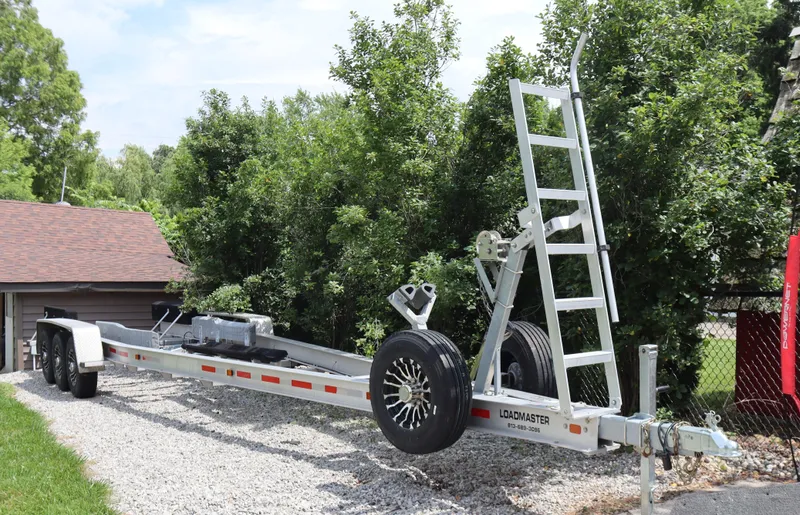  Yacht Photos Pics Trailer for 2022 Contender 35 ST boat, parked on gravel driveway near trees.