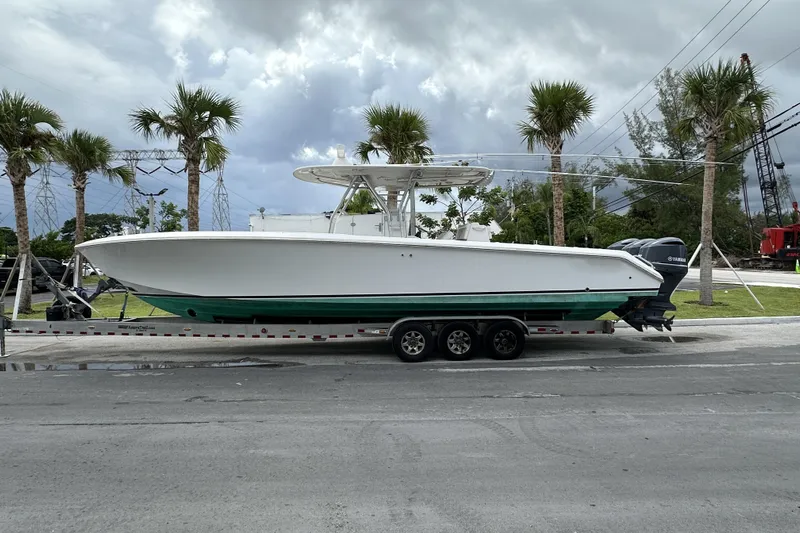  Yacht Photos Pics 2013 Bahama 37CC boat on trailer, parked near palm trees under cloudy sky.