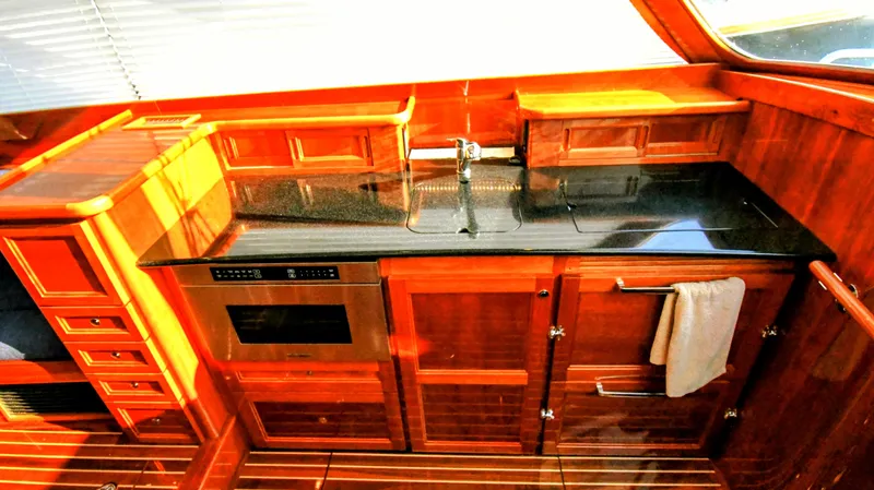 My Lisa Yacht Photos Pics Luxurious 2022 Hinckley Talaria 43 yacht kitchen with sleek wood cabinetry and modern appliances.
