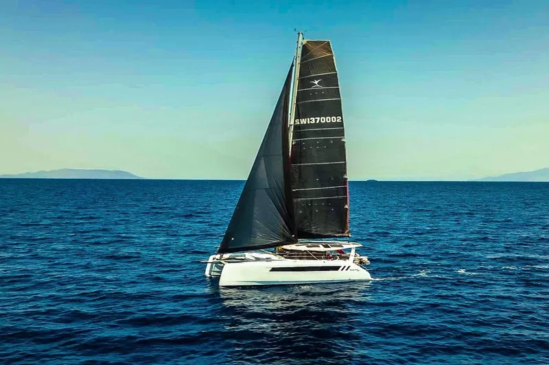 Ruby Rose 2 Yacht Photos Pics 2023 Seawind 1370 catamaran sailing on open sea under clear blue sky.