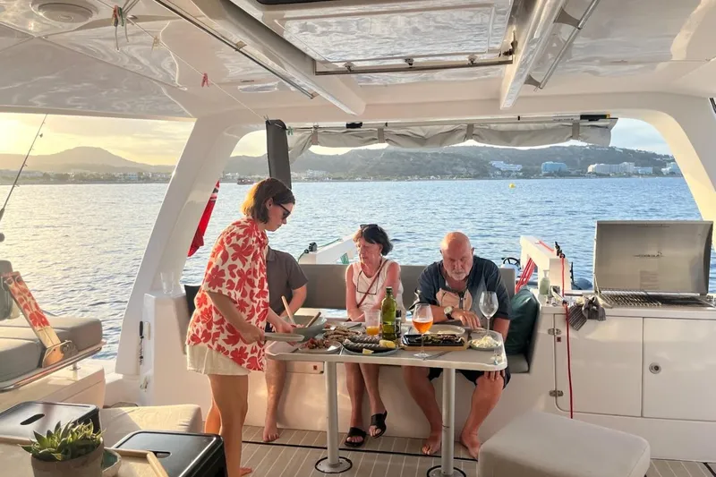 Ruby Rose 2 Yacht Photos Pics People dining on a Seawind 1370 catamaran, enjoying a meal with a scenic ocean view.