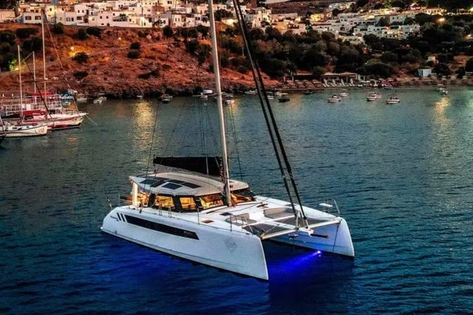 Ruby Rose 2 Yacht Photos Pics 2023 Seawind 1370 catamaran illuminated at dusk in a scenic coastal bay.