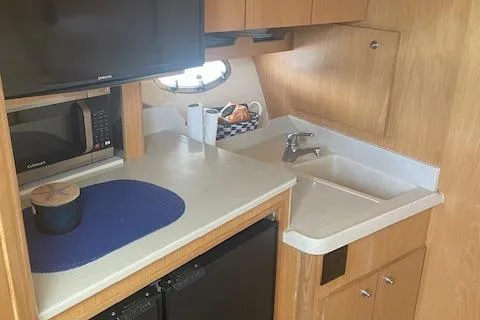 "moxie" Yacht Photos Pics 1998 Tiara Yachts 35 Open Hardtop kitchen with microwave, sink, and wooden cabinetry.