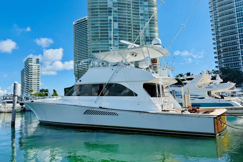 Kickback Yacht Photos Pics 2004 Viking 65 Convertible yacht docked in a marina with skyscrapers in the background.