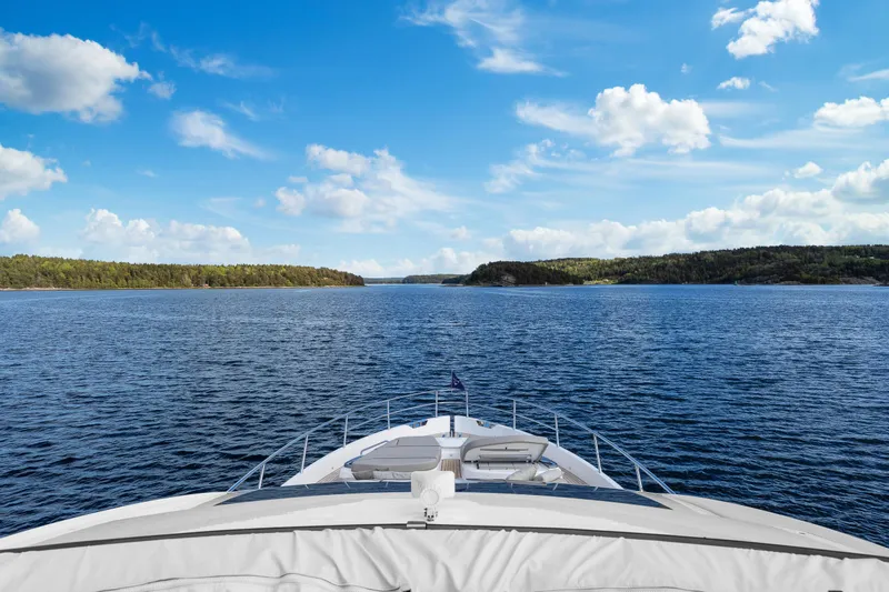 S72515 Yacht Photos Pics Bow view of 2023 Princess S72 yacht cruising on a serene lake under a blue sky.