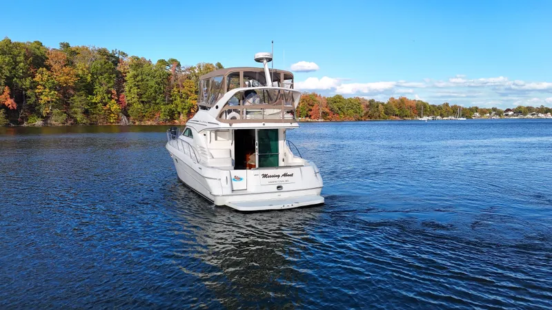 Messing About Yacht Photos Pics 2003 Sea Ray 400 Sedan Bridge yacht cruising on a scenic lake with autumn foliage.