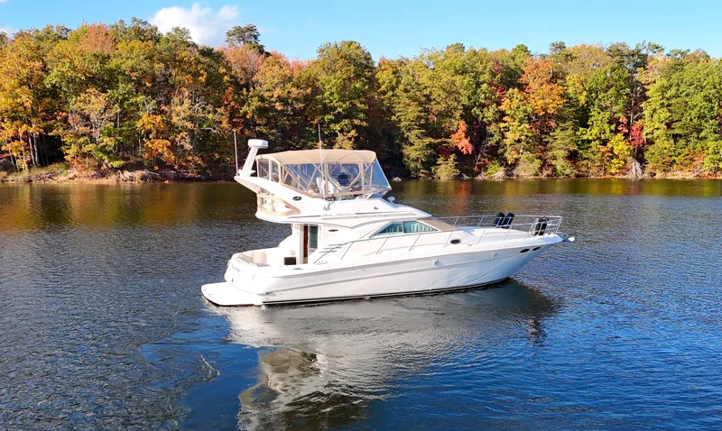 Messing About Yacht Photos Pics 2003 Sea Ray 400 Sedan Bridge yacht on a serene lake with autumn foliage.