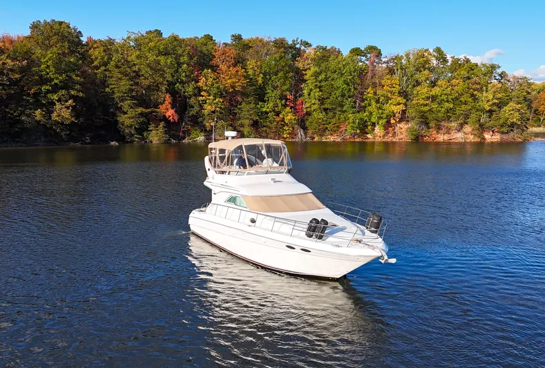 Messing About Yacht Photos Pics 2003 Sea Ray 400 Sedan Bridge yacht cruising on a scenic lake with autumn foliage.