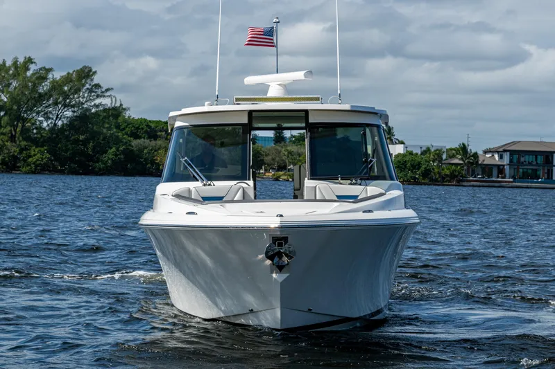 Never Say Never Yacht Photos Pics 2021 Tiara Yachts 34 LX cruising on a scenic waterway with an American flag.