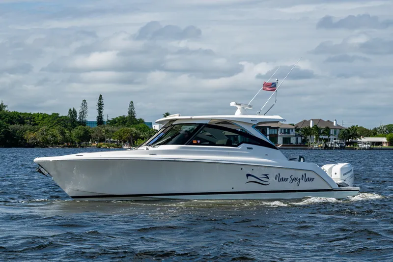 Never Say Never Yacht Photos Pics 2021 Tiara Yachts 34 LX cruising on a scenic waterway with American flag.