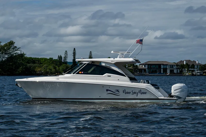 Never Say Never Yacht Photos Pics 2021 Tiara Yachts 34 LX cruising on a scenic waterway with houses in the background.