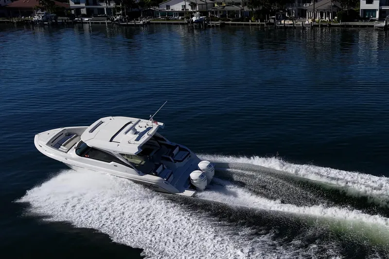 Never Say Never Yacht Photos Pics 2021 Tiara Yachts 34 LX cruising on calm waters near residential docks.