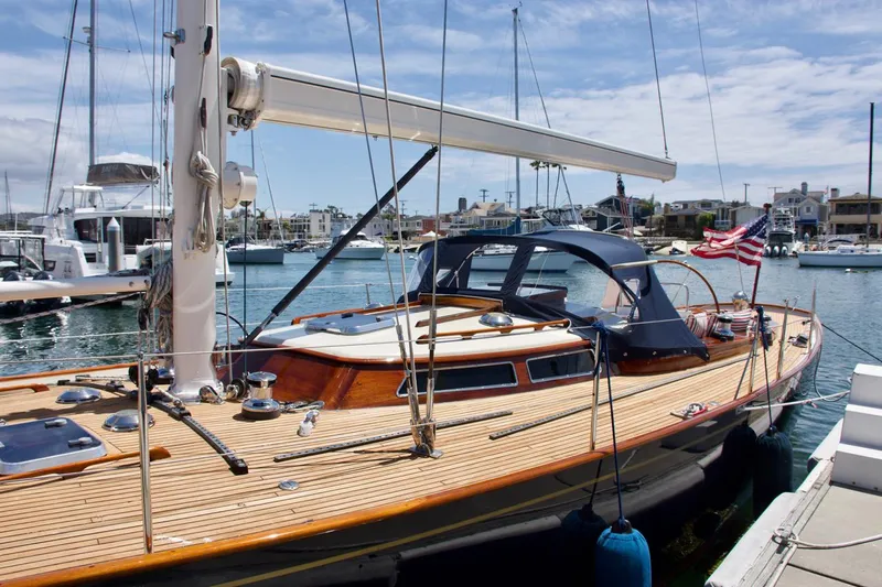 Volunteer Yacht Photos Pics Custom 1996 Bruckmann Yachts sailboat docked in a marina, featuring a wooden deck and American flag.