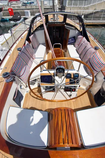 Volunteer Yacht Photos Pics 1996 Custom Bruckmann Yachts cockpit with wooden wheel, striped cushions, and navigation instruments.