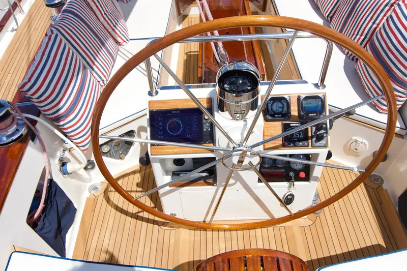 Volunteer Yacht Photos Pics Steering wheel of 1996 Custom Bruckmann Yacht with striped cushions and navigation instruments.