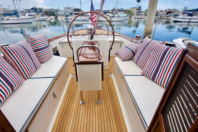 Volunteer Yacht Photos Pics Luxurious 1996 Custom Bruckmann Yacht with striped cushions and wooden deck in a marina setting.