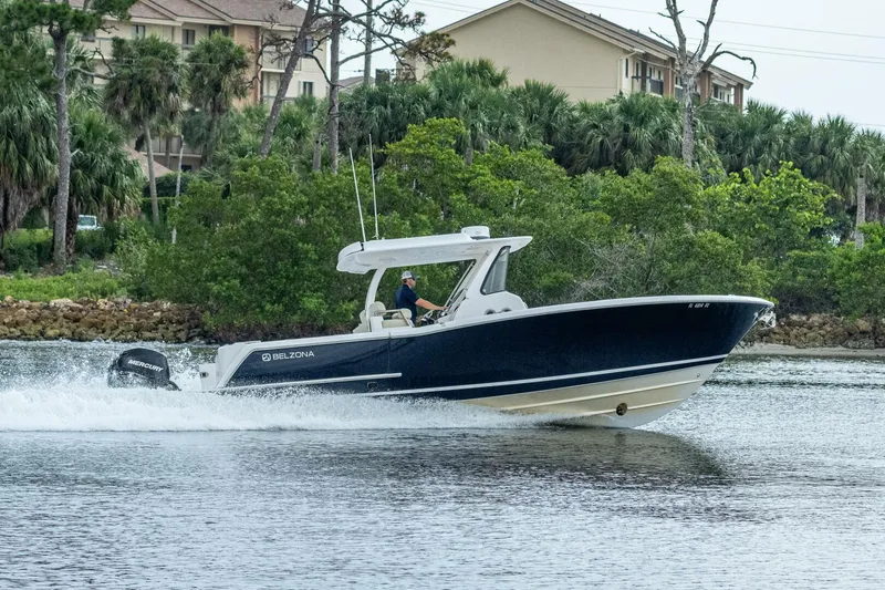  Yacht Photos Pics 2015 Belzona 32C boat cruising on a lake near a forested shoreline.