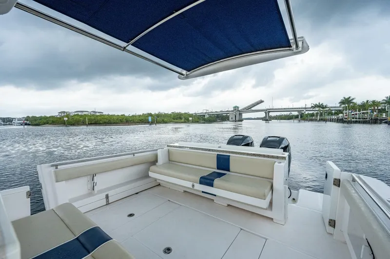  Yacht Photos Pics 2015 Belzona 32C boat with blue canopy and seating, docked near a bridge.