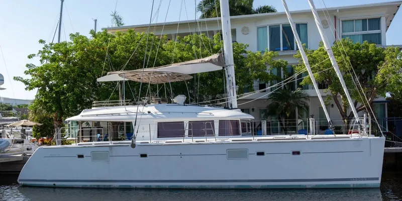 Sea Serenity Yacht Photos Pics 2012 Lagoon 560 catamaran docked near waterfront house, surrounded by lush greenery.