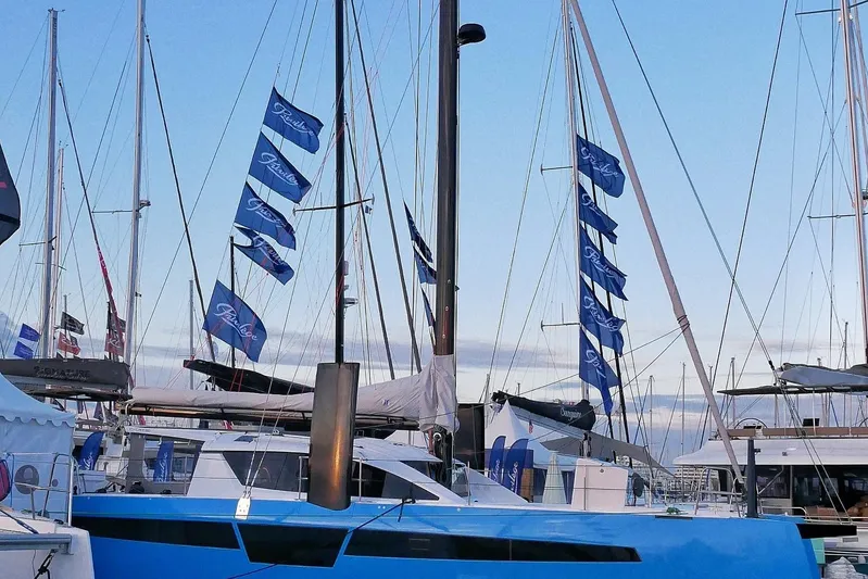 Aurora Yacht Photos Pics 2025 C-Catamarans 48 yacht with blue hull and multiple flags at a marina.