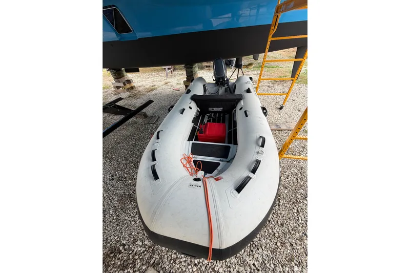 Aurora Yacht Photos Pics Inflatable boat under a 2025 C-Catamarans 48, on gravel with scaffolding nearby.