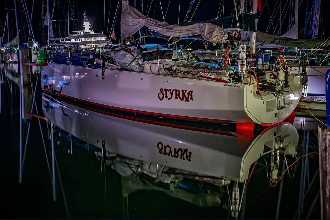 2020 Dehler 30 OD sailboat "Styrka" docked at night, reflecting on calm water.