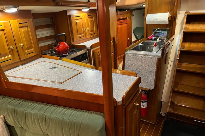 Thumper Yacht Photos Pics Interior of 2001 Tartan 3700 Sloop with wooden cabinetry and compact kitchen area.