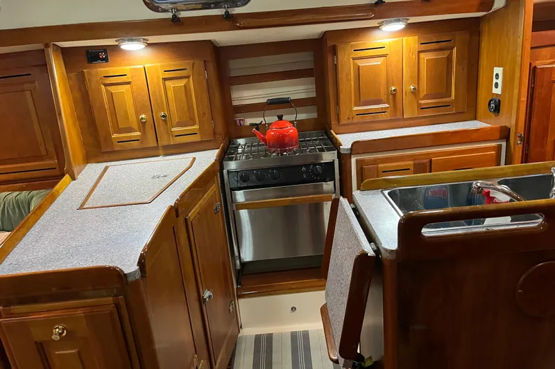 Thumper Yacht Photos Pics Cozy 2001 Tartan 3700 Sloop kitchen with wooden cabinets and stainless steel appliances.