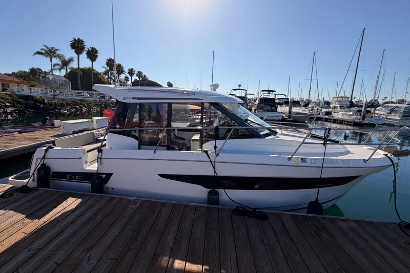  Yacht Photos Pics 2020 Jeanneau NC 895 boat docked at marina, surrounded by other vessels.