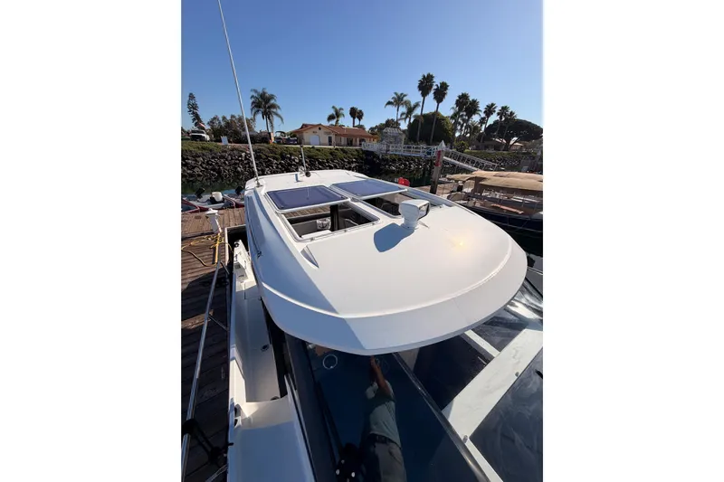  Yacht Photos Pics 2020 Jeanneau NC 895 boat docked, showcasing sleek design and sunroof under clear blue sky.