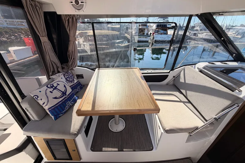  Yacht Photos Pics Interior of 2020 Jeanneau NC 895 boat with dining area and nautical-themed cushions.