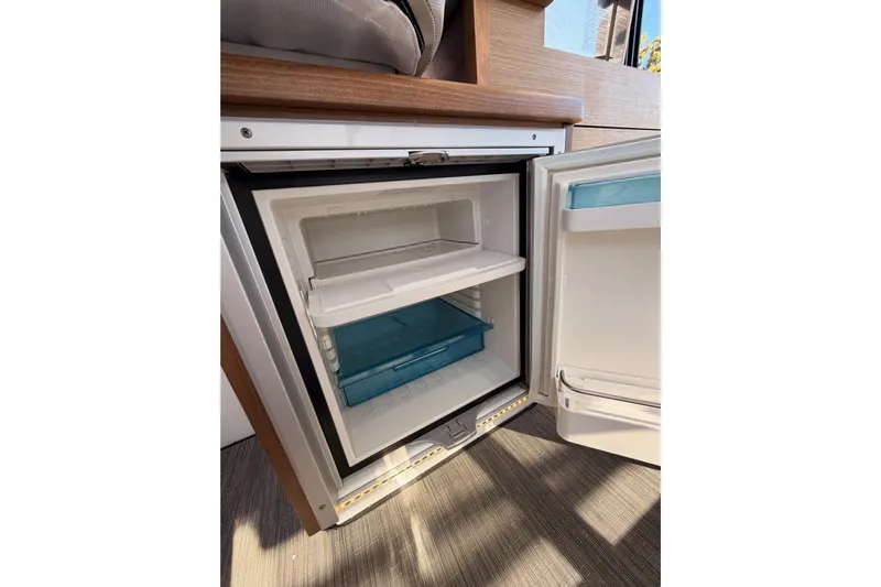  Yacht Photos Pics Open refrigerator inside 2020 Jeanneau NC 895 boat, showcasing storage compartments.