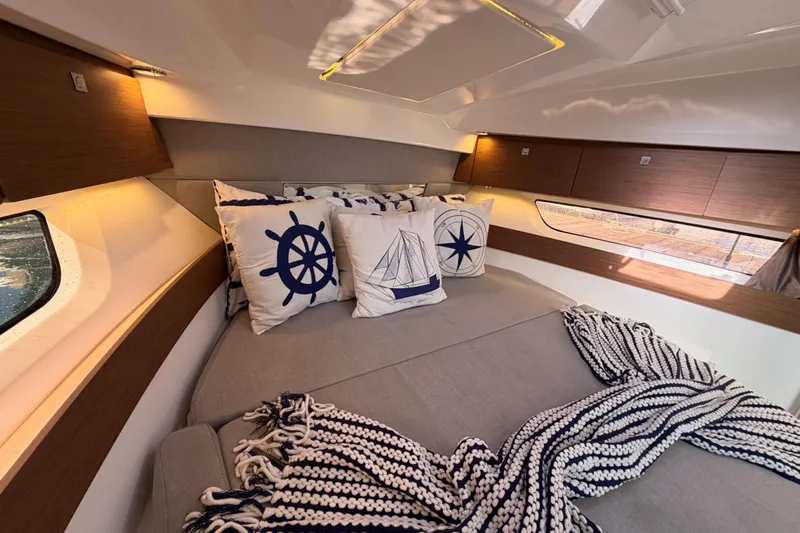  Yacht Photos Pics Cozy interior of 2020 Jeanneau NC 895 with nautical-themed pillows and blanket.