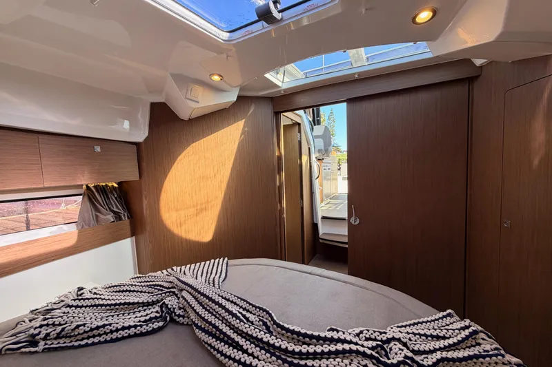  Yacht Photos Pics 2020 Jeanneau NC 895 cabin interior with skylight, wood paneling, and cozy bedding.