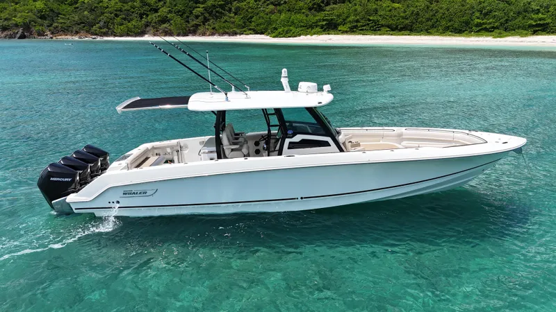  Yacht Photos Pics 2020 Boston Whaler 380 Outrage boat cruising in clear turquoise waters near a sandy beach.