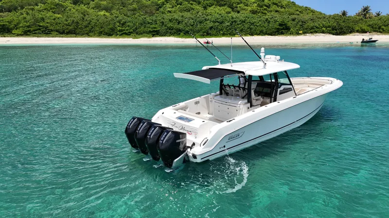  Yacht Photos Pics Boston Whaler 380 Outrage 2020 cruising in clear turquoise waters near a sandy beach.