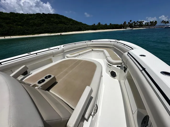  Yacht Photos Pics 2020 Boston Whaler 380 Outrage boat with spacious seating, anchored near a tropical beach.