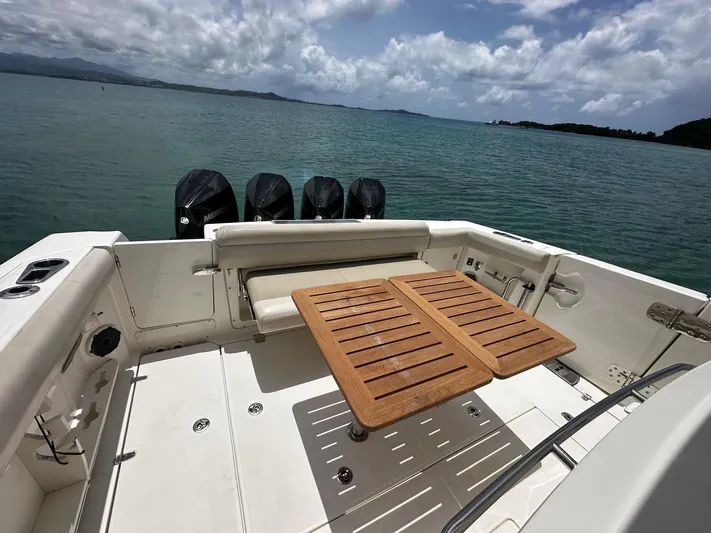 Yacht Photos Pics 2020 Boston Whaler 380 Outrage boat deck with wooden table, overlooking serene ocean view.
