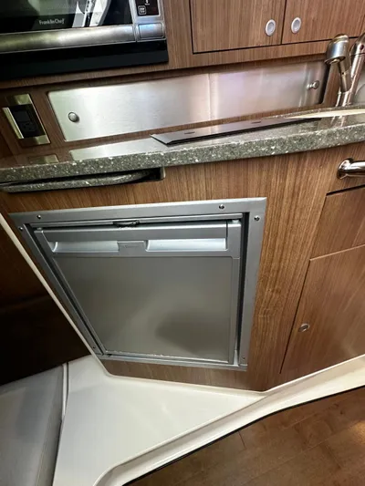  Yacht Photos Pics 2015 Boston Whaler 315 Conquest interior kitchen with wood cabinetry and stainless steel appliances.