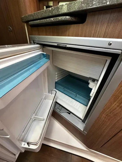  Yacht Photos Pics Compact refrigerator inside 2015 Boston Whaler 315 Conquest boat, featuring wooden cabinetry and modern design.