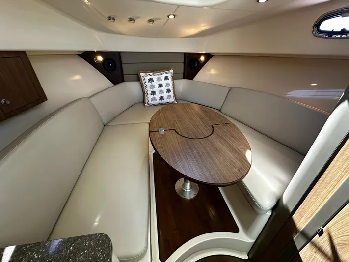  Yacht Photos Pics 2015 Boston Whaler 315 Conquest cabin interior with beige seating and wooden table.