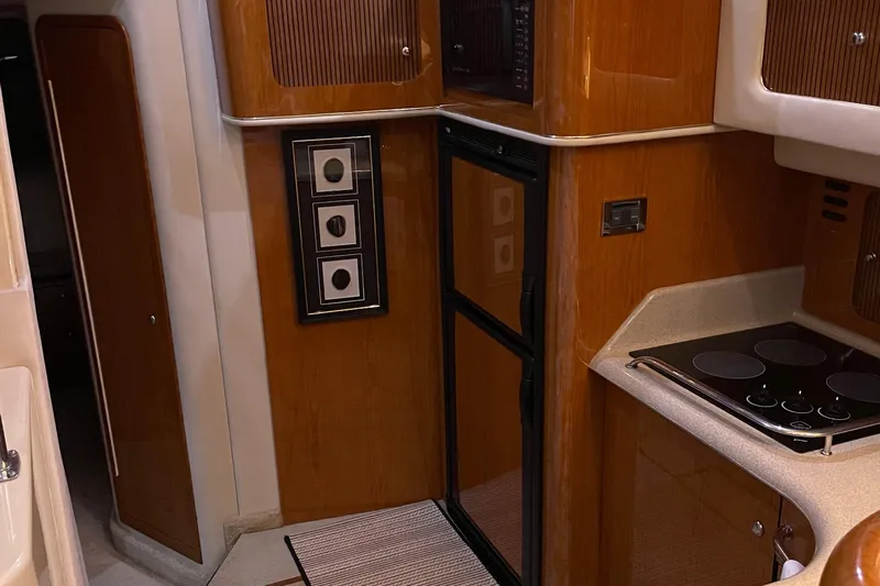  Yacht Photos Pics Interior of 2000 Sea Ray 400 Sedan Bridge yacht kitchen with wood cabinetry and stovetop.